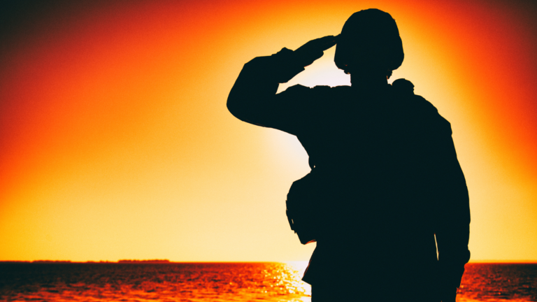 Silhouette d’un soldat saluant au coucher du soleil, symbolisant l’honneur, le devoir et le courage. Une illustration évocatrice pour un article sur les héros blessés et leur quête de rédemption en Romance Militaire