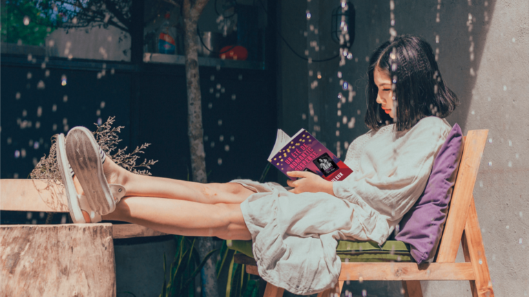 Lectrice installée à l'ombre en train de lire un roman de romance pendant une journée de canicule.